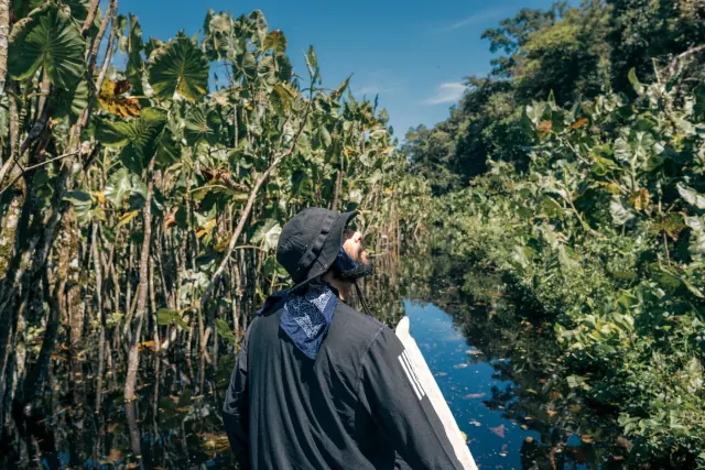 Canoa navegando un canal estrecho de la selva amazónica