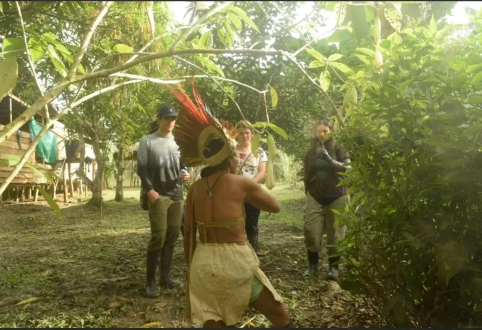 Integrante de la comunidad tikuna de Paraíso con tocado de plumas guiando a visitantes por la selva