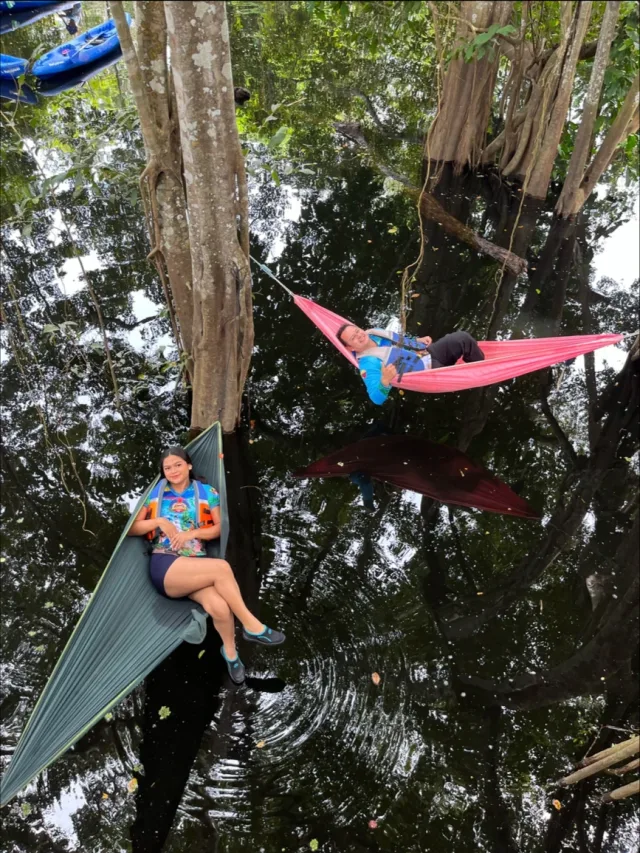 Sergio Andres Rojas Montero y una integrante de su equipo descansando en hamacas sobre un bosque inundado del Amazonas